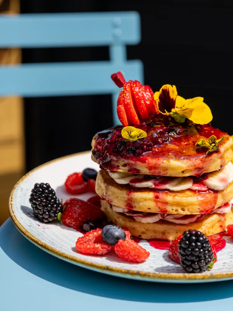 Stack of berry pancakes with fresh berries at Cloud 7, a fully halal brunch spot in London